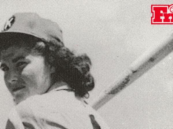 lack and white photo of Marge Villa at bat. She wears a baseball hat and uniform.