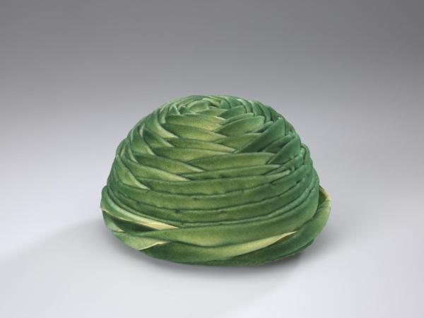 Green velveteen hat with layers of fabric wrapped in a circular design