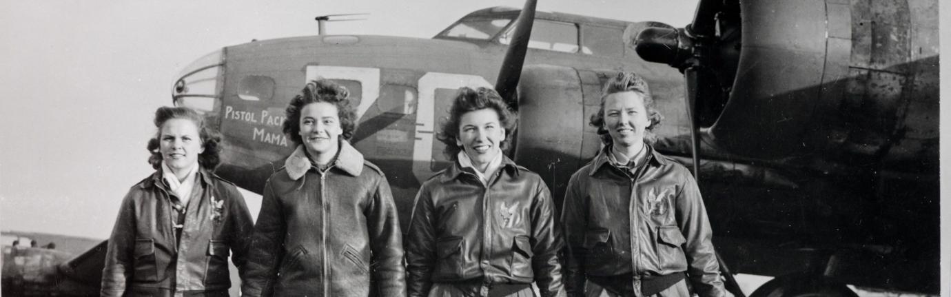 Black and white image of 4 female pilots walking in front of a plane