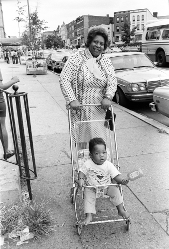 Black and white photo of Casilda Luna pushing her toddler grandson in a stroller.