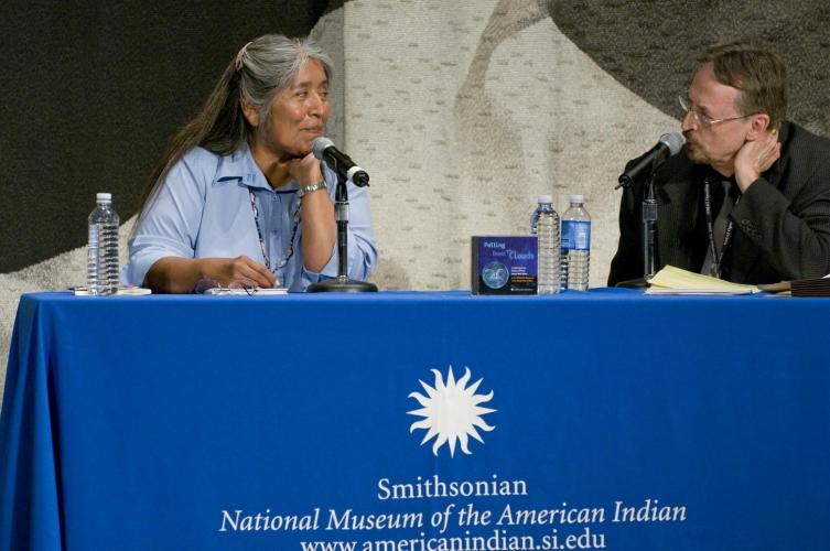 Dr. Ofelia Zepeda smiles as Terence Winch speaks. They sit at a table in the National Museum of the American Indian.