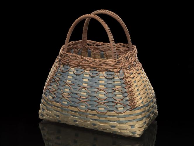 Photo of a woven basket with details including light and dark tan reeds and blue dyed reed