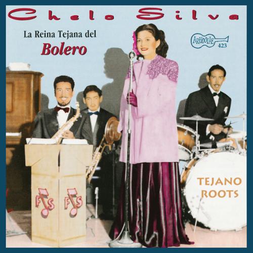 Chelo Silva sings at a microphone in front of a band including a saxophone player, a trumpet player, and a drummer. Silva wears a dress, pink jacket, pink gloves, and flowers in her hair.