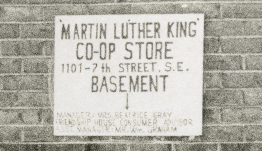 Sepia photo of sign on a brick wall. Sign reads &quot;Martin Luther King Co-Op Store 1101 - 7th Street, S.E. Basement&quot;