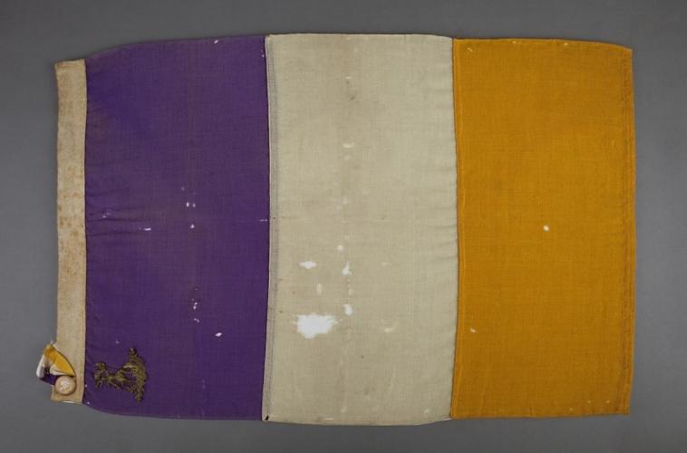 Old flag with three  colored segments of purple, white, and golden yellow .