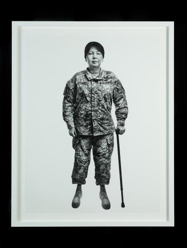 Black and white full body photo of Tammy Duckworth in her army uniform and using a cane