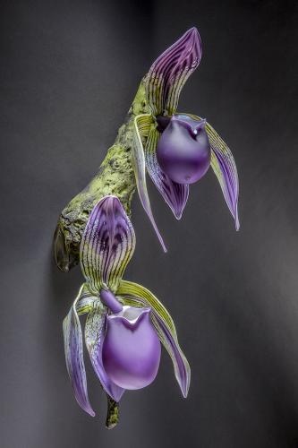 Glass sculpture of two purple orchid flowers hanging on a branch