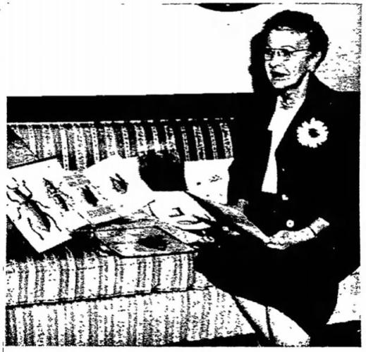  Blurry photocopy of Aime Awl seated on a couch next to illustrations propped up in the seats beside her. 