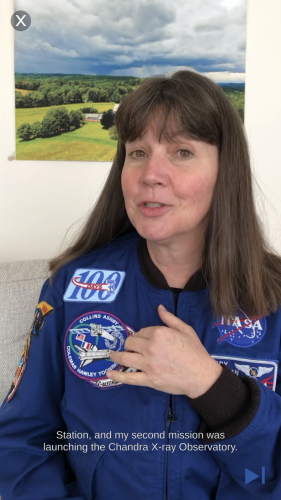 alt=&quot;Cady Coleman speaks to the camera in this app screenshot. She wears a NASA uniform and points to one of the patches on her uniform.&quot;