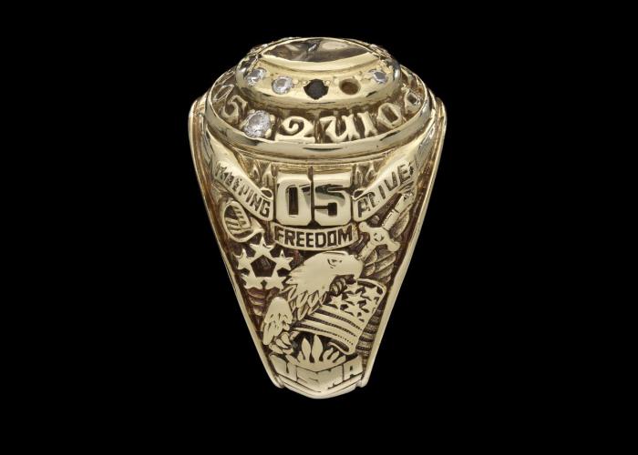 Gold ring with some stones missing. There&#039;s an image of an eagle and the text: 05 Keeping Freedom Alive