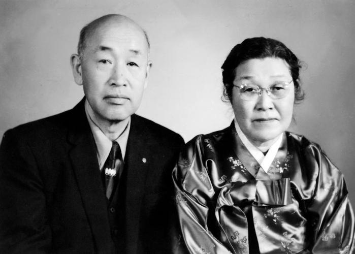 Black and white portrait of Dr. Chung and Sung Hark (Lee) Kang sitting side by side, unsmiling, facing the camera.    