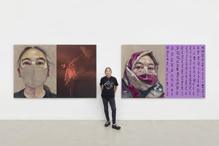  Hung Liu standing between two large and colorful self-portraits behind her