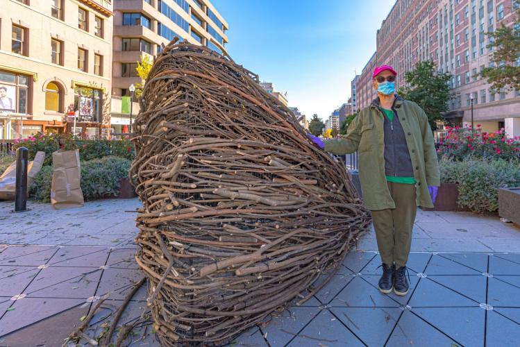 Maren Hassinger stands next to Monument, made of woven branches