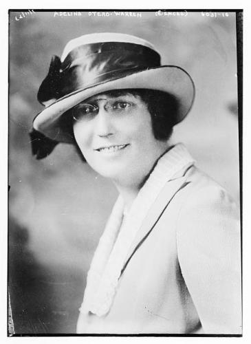 Black and white photo of Adelina Otero-Warren smiling while wearing a blazer and a hat with a black bow.