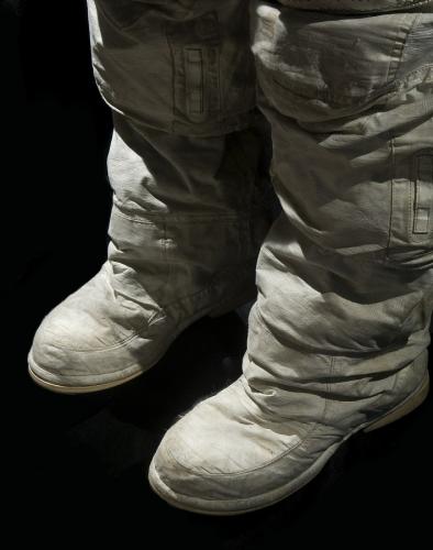 Color photograph of the outer white layer of boots and legs from the knee down of the spacesuit.